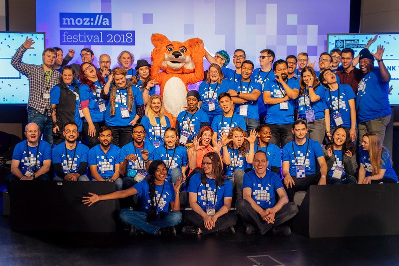 All the volunteers from MozFest 2018, standing on stage cheering.