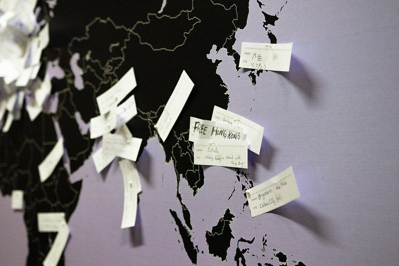 Photo by Connor Ballard-Pateman of a world map with pins in cities with little notes