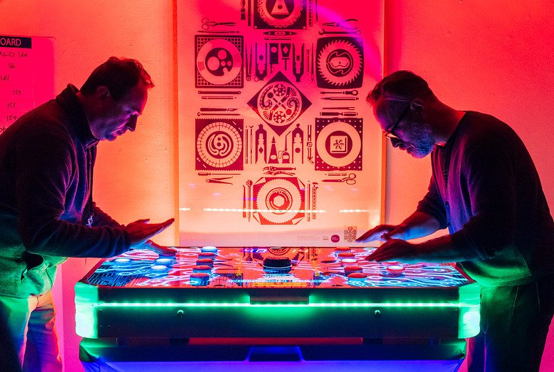Two people playing a game lite up by neon and black lights.