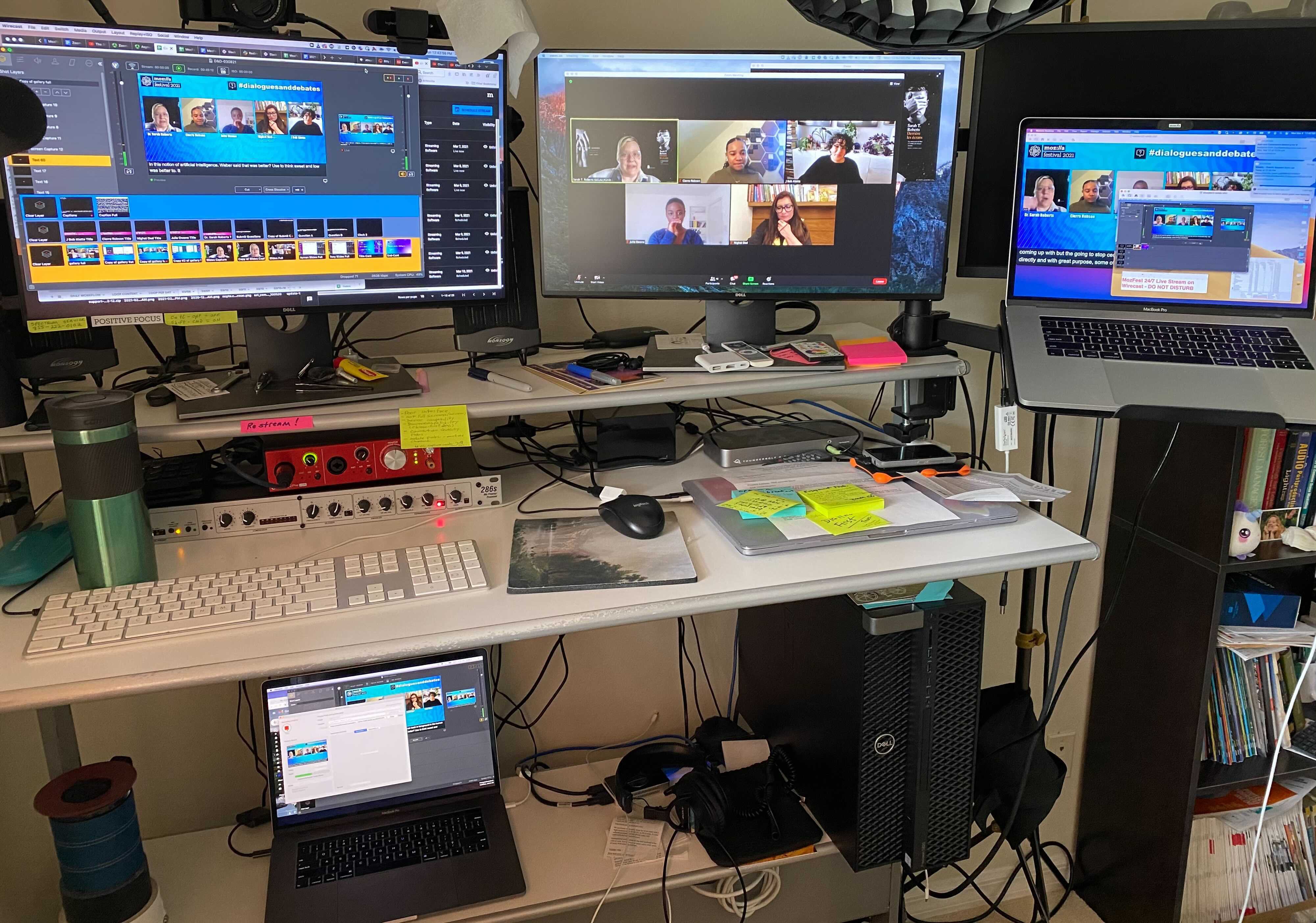 Live stream A/V workstation with multiple monitors on top of and below desk showing various views of the behind the scenes of a live broadcast