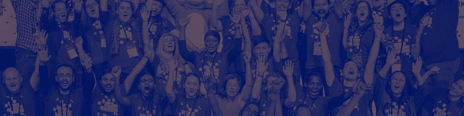 A group of volunteers wearing a MozFest t-shirt that says 'data done right' are stood on staged cheering with their arms raised.